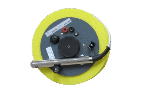 The Water Level Meter Mini - With Start / Stop System is a round, yellow and grey electronic device featuring labelled knobs, ports, and a metal rod attached—shown from above on a plain white background.