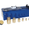 The Surface Shear Test Apparatus features a blue mechanical device with a metal dial, sliding mechanism, six brass weights of assorted sizes, and two round black and yellow pads, displayed on a white background.