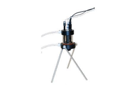 The Flow Through Cell Compact, a small scientific device with attached wires, is mounted on a tripod stand with three metal legs against a plain white background.