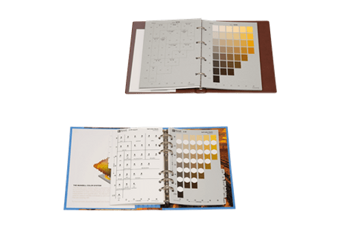 Two open Soil Colour Books with plastic sheets; the top shows greyscale and brown gradient swatches, while the bottom displays circular brown and grey swatches over a photo background.